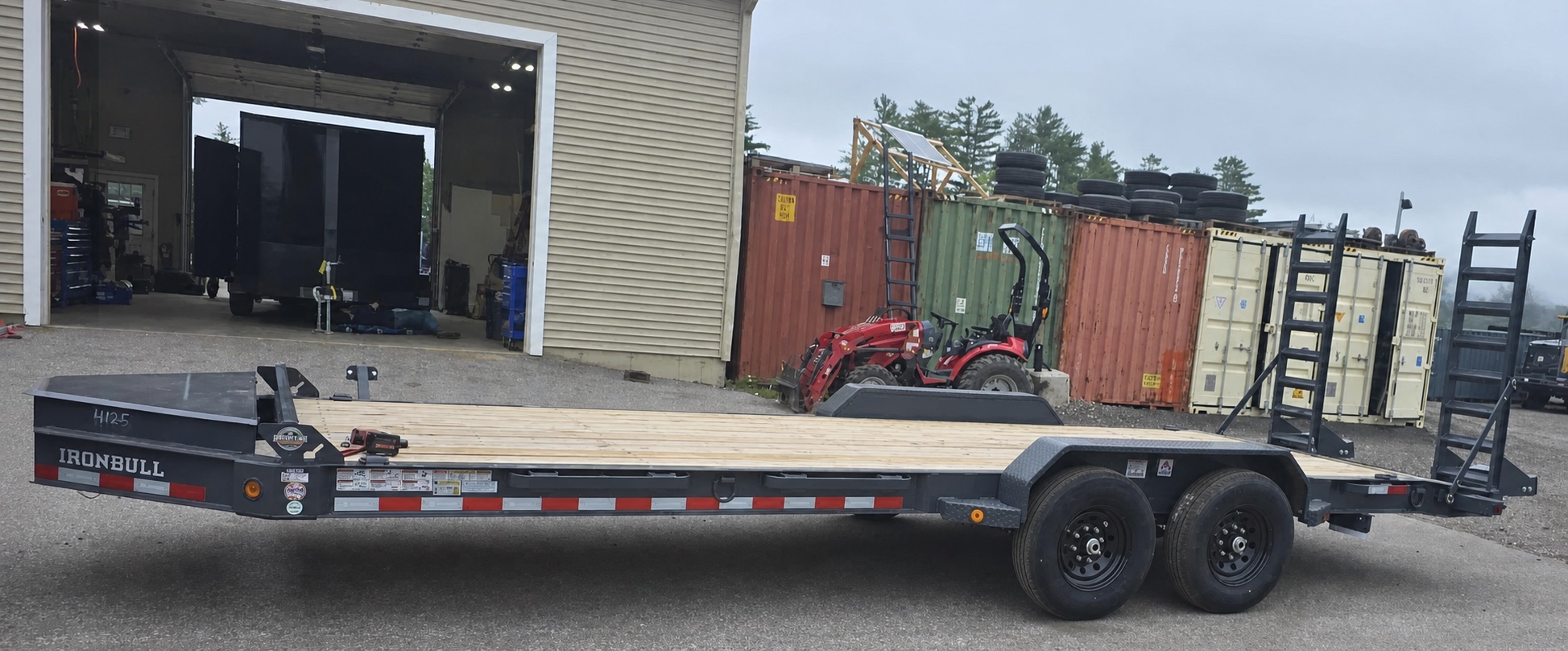 Full black Iron Bull equipment trailer with a wood deck and loading ramps