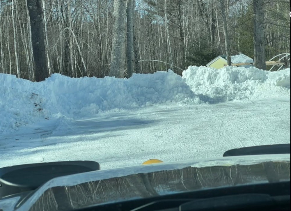 A wide residential drive cleared between high snowbanks